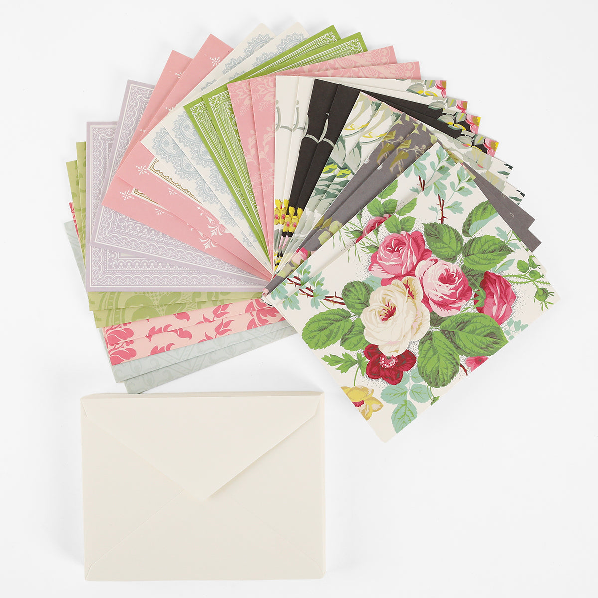 A stack of Pretty Pattern A2 Cards and Envelopes, displaying decorative floral designs, is fanned out above a single plain ivory envelope on a white background.