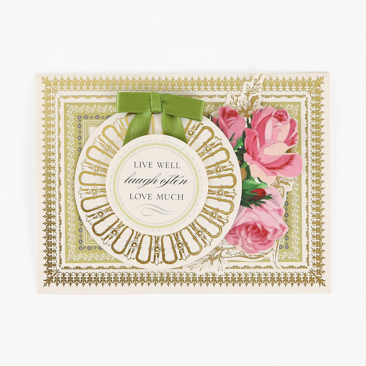 Certainly! Here’s a revised version using the provided product name: Greeting card featuring a gold decorative border, pink roses, and a round tag with green ribbon that reads “Live well, laugh often, love much.” From our Pretty Pattern A2 Cards and Envelopes collection, these handmade cards are paired with elegant ivory envelopes.