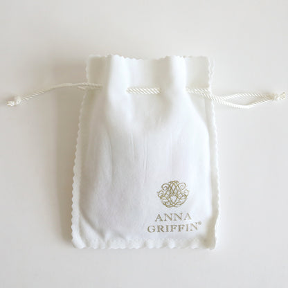 A compact white drawstring pouch with scalloped edges, adorned with a decorative logo and the name "Anna Griffin" in gold on the front, perfect for accommodating pieces from the Set of 2 Gold Necklaces Kit or as part of a jewelry collection.