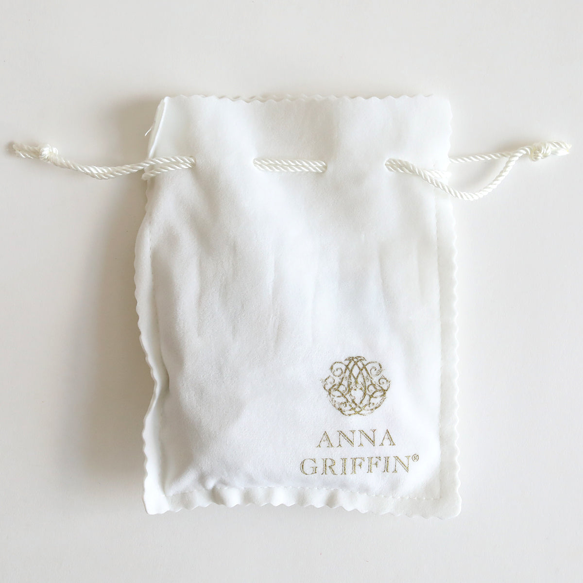 A white drawstring bag adorned with the "Anna Griffin" logo and text, ideal for keeping your Set of 2 Silver Necklaces Kit or highlighting statement necklaces and silver-tone pendants.