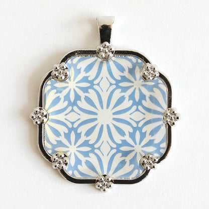 Discover the perfect statement necklace with our Set of 2 Silver Necklaces Kit, featuring a pendant adorned with a striking blue and white geometric floral pattern set in an ornate silver-tone frame.