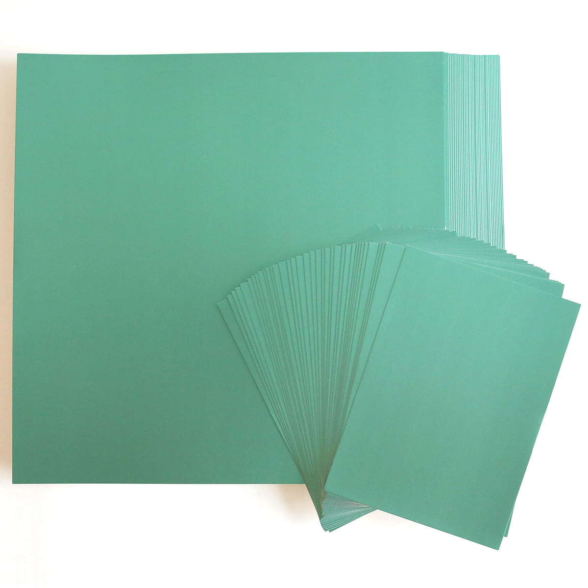 A large stack of Foil Matte Cardstock in Paris Green, measuring 12" x 12", on a white background with a portion fanned out on the right.