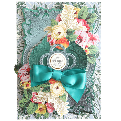 This elegantly crafted design features intricate floral cutouts layered on a backdrop made from Paris Green foil matte cardstock. Adorned with a teal bow and vibrant flowers, it beautifully displays the "You Brighten My Day" message against the 12" x 12" sheets.