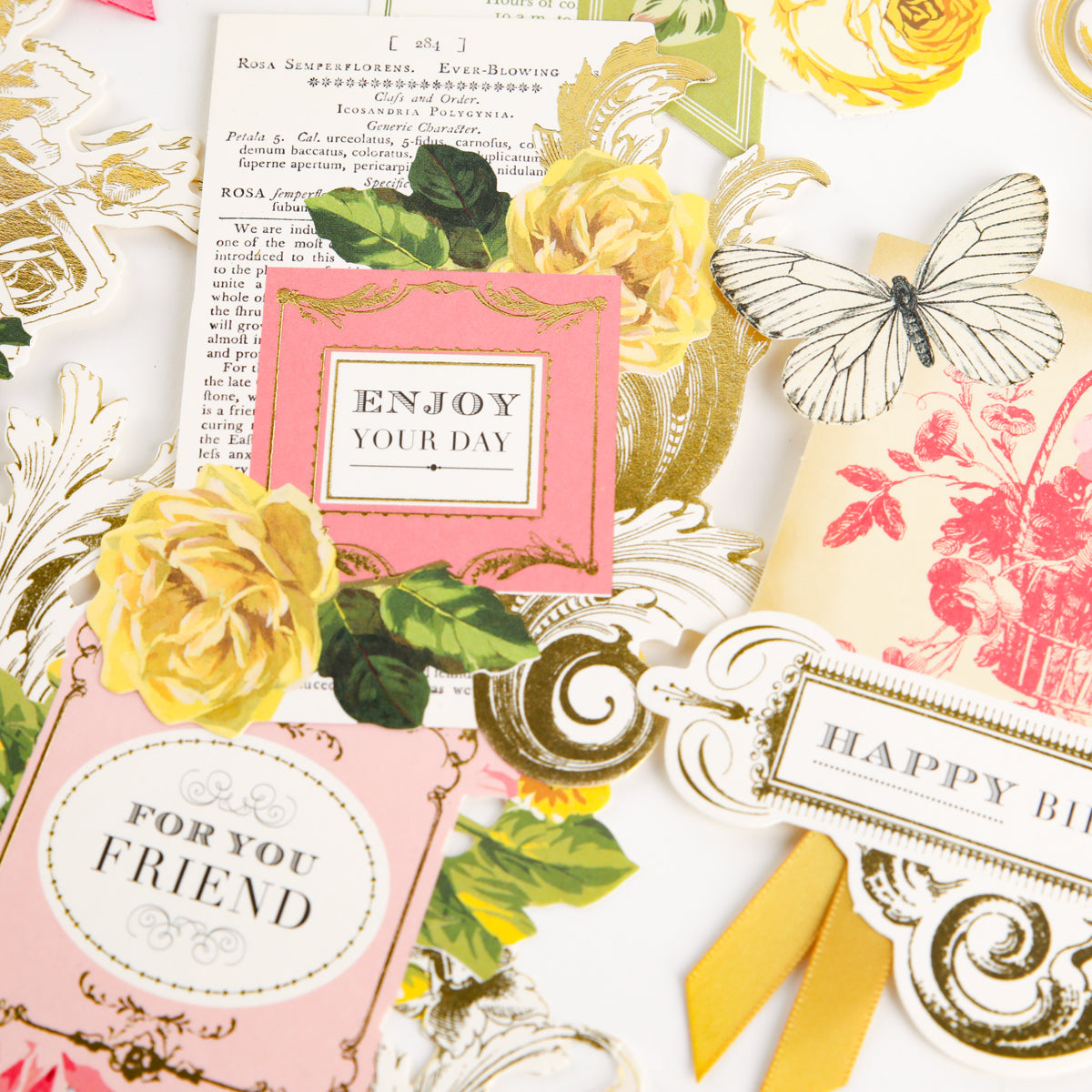 A flat lay of Birthday Collage Card Toppers features decorative floral cards and tags with messages such as “ENJOY YOUR DAY” and “FOR YOUR FRIEND,” accented by yellow roses, butterfly illustrations, and charming die cut details for an elegant vintage collage embellishment style.