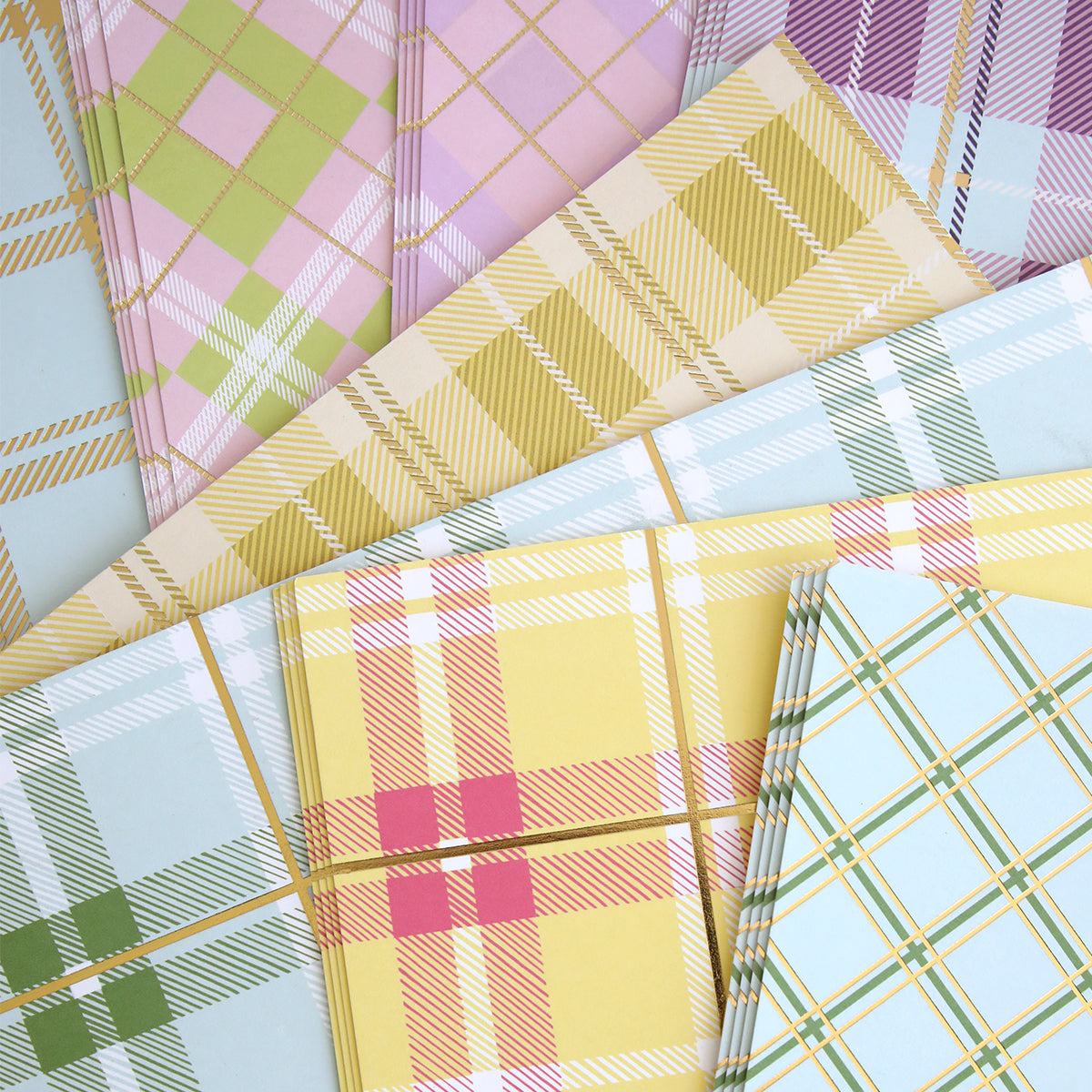 The Pastel Plaid 12x12 Cardstock features assorted pastel plaid patterns with gold foil accents in vibrant colors like pink, green, yellow, and blue—ideal for adding a touch of elegance to any project.