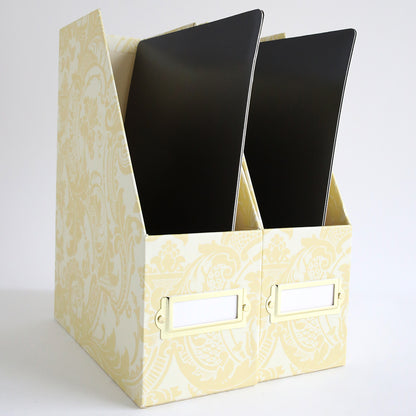 Two ivory damask die storage boxes, each with a front label and containing a black file folder for magnetic sheets or oversized dies, are positioned side by side on a white background.