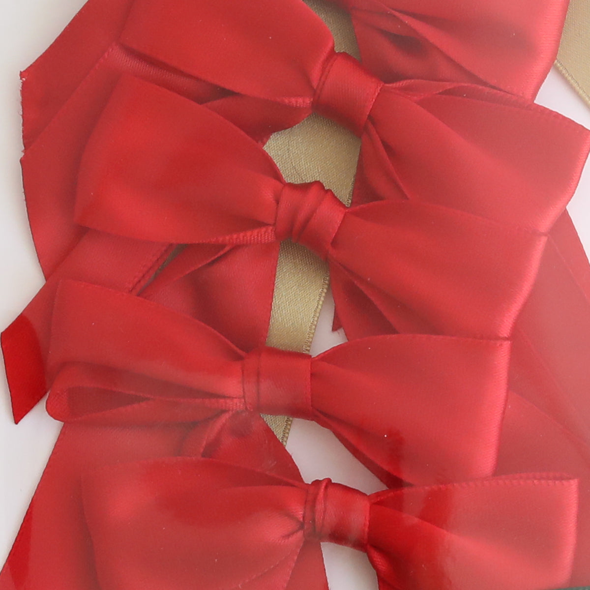 Four Medium Pre-Tied Christmas Bows in red and gold are arranged vertically with overlapping layers, featuring a shimmering gold ribbon in the background.