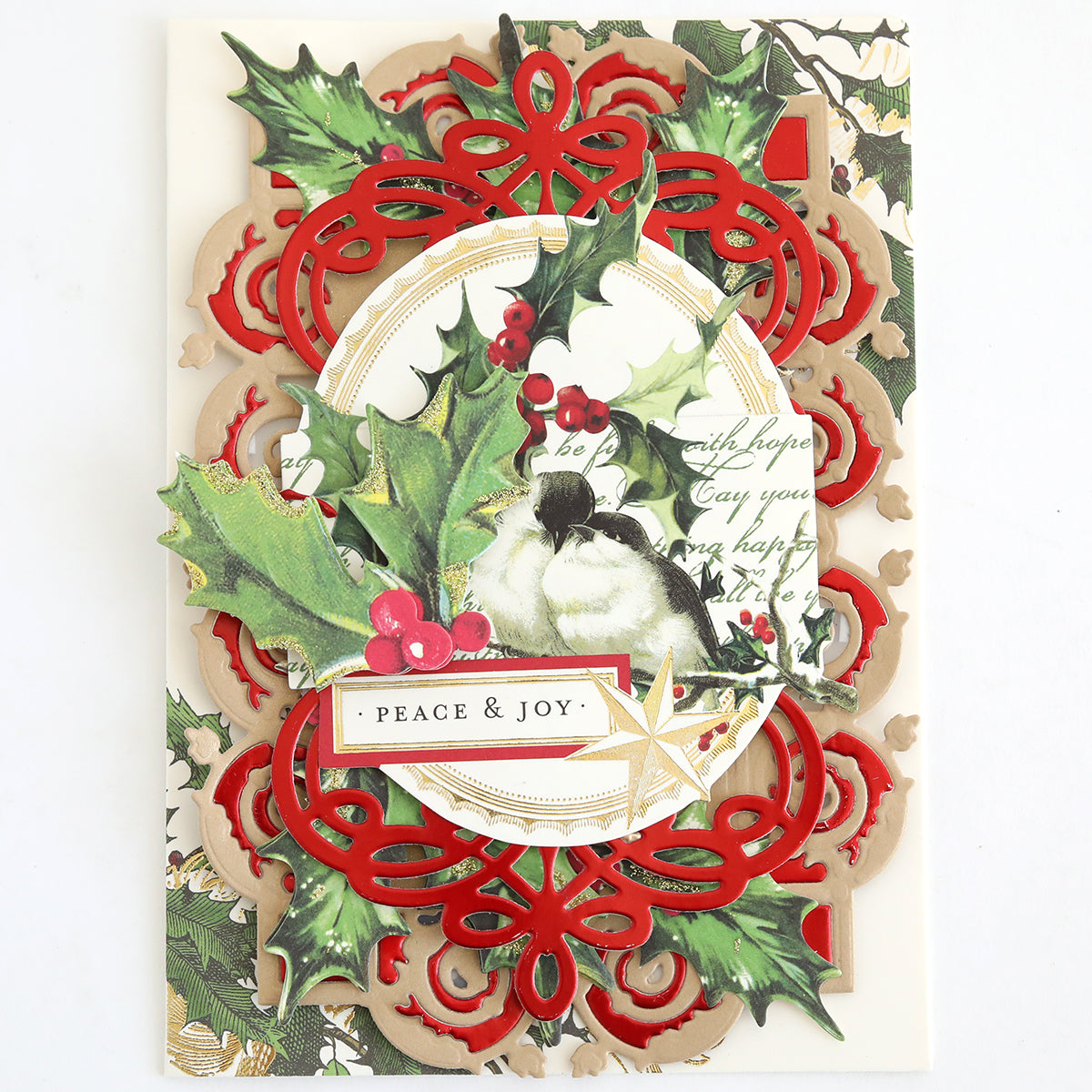The Christmas Engravings Collage Card Toppers feature a beautifully designed bird surrounded by holly leaves, red berries, and intricate red and gold patterns, with a “PEACE & JOY” label at the center—ideal for creating handmade Christmas cards or adding an elegant touch to your festive projects.
