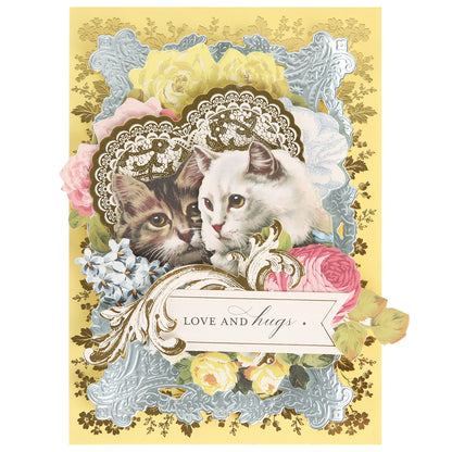 A decorative card features two cats surrounded by ornate lace patterns, flowers, and a banner reading "LOVE and hugs" on an ice blue background, beautifully crafted from the luxurious Ice Blue Foil Cardstock Bundle for a touch of elegance.