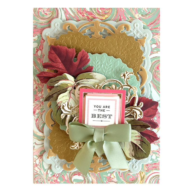 A decorative greeting card with an ornate design, featuring multiple embossed layers, a green bow, and the text "You are the best" in the center. Crafted using Harvest Cut & Emboss Folders, the card is adorned with red and green leaf embellishments.