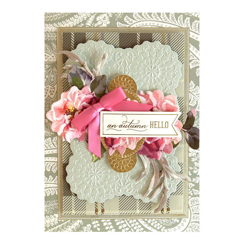 A decorative card featuring a pink bow, pink flowers, lace patterns, and the text "an autumn HELLO" on embossed card layers created with the Harvest Cut & Emboss Folders on a layered, textured background.