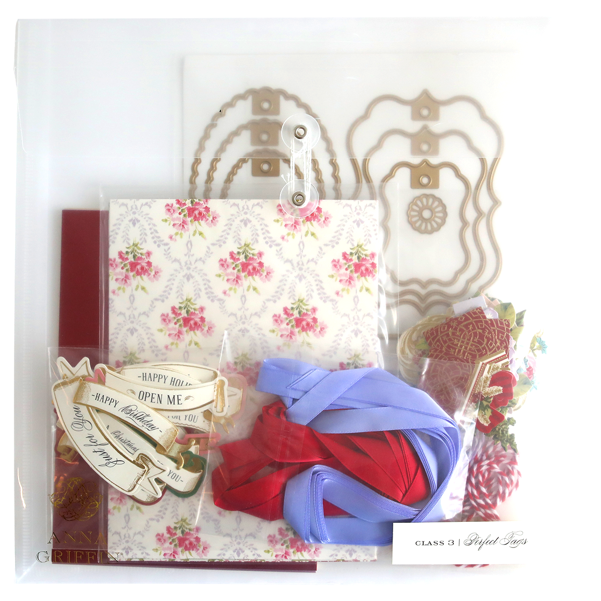 A clear box containing a variety of items, beautifully adorned with the Gift Tag Compendium Class Materials and Dies for that special touch. Perfect as a handmade gift to surprise and delight your loved ones.