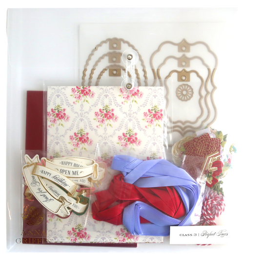 A clear box containing a variety of items, beautifully adorned with the Gift Tag Compendium Class Materials and Dies for that special touch. Perfect as a handmade gift to surprise and delight your loved ones.