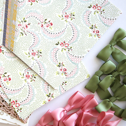 A collection of green and pink papers, bows, and supplies for creating Beautiful Birthday Class Materials and Dies and birthday cards from Anna Griffin.