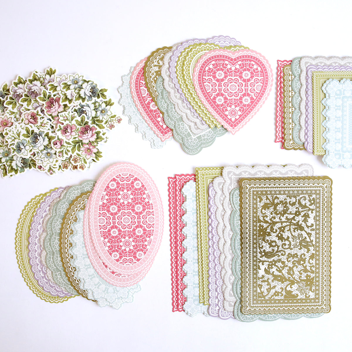 A collection of Lace Doily Embellishments and paper flowers on a white surface, perfect for creating Valentine's cards.