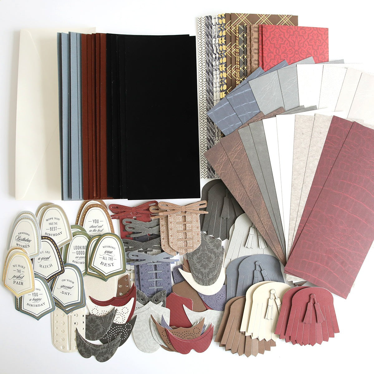 A variety of cardstock and paper crafting materials are arranged, including tags, decorative die-cut shapes, and patterned sheets in different colors and textures. The collection features elements from the Paper Wingtips Refill Kit, perfect for adding 3D embellishments to your projects.