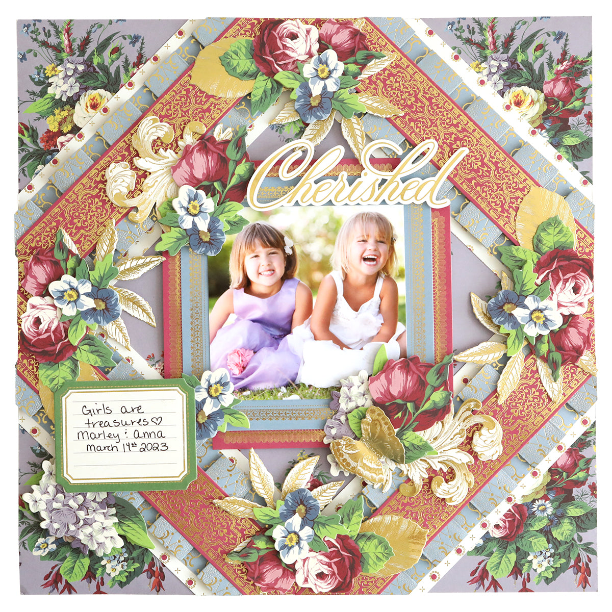 A scrapbook page created with the Simply Astrid Scrapbooking Kit, showcasing two smiling children, adorned with vibrant floral decorations and the word "Cherished." A note reads: "Girls are treasures. Morley & Anna. March 12, 2023.