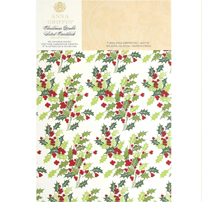 A sheet of Christmas Double Sided 300gsm Cardstock featuring a festive design of green holly leaves and red berries. The packaging label includes the brand name and manufacturing details, perfect for AG Members who appreciate high-quality, double-sided papers.