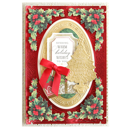 A beautifully handmade Christmas card with holly designs, featuring a gold border and Christmas tree, a red ribbon, and a message that reads, "Sending warm holiday wishes to you," made even more special with intricate Christmas Greetings 3D Concentric Dies.