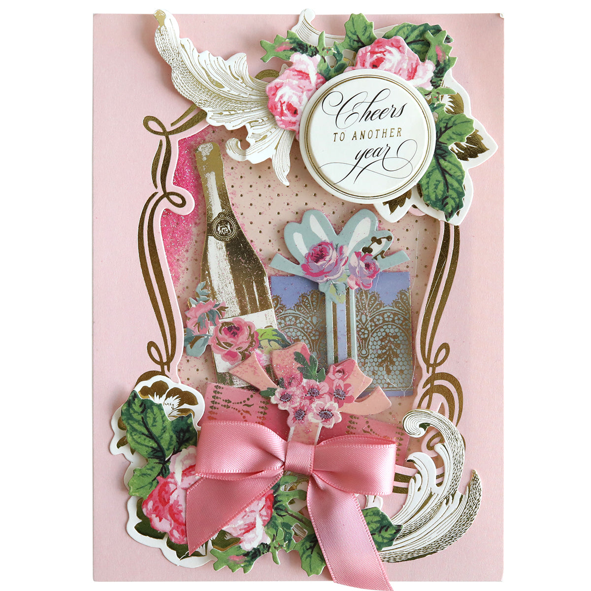 The Shaker Card Supply Kit includes a decorative, pink greeting card adorned with floral designs, a champagne bottle, and a ribbon bow, featuring the message "Cheers to another year!". Ideal for DIY shaker cards enthusiasts, this charming piece adds a personalized touch to any celebration.