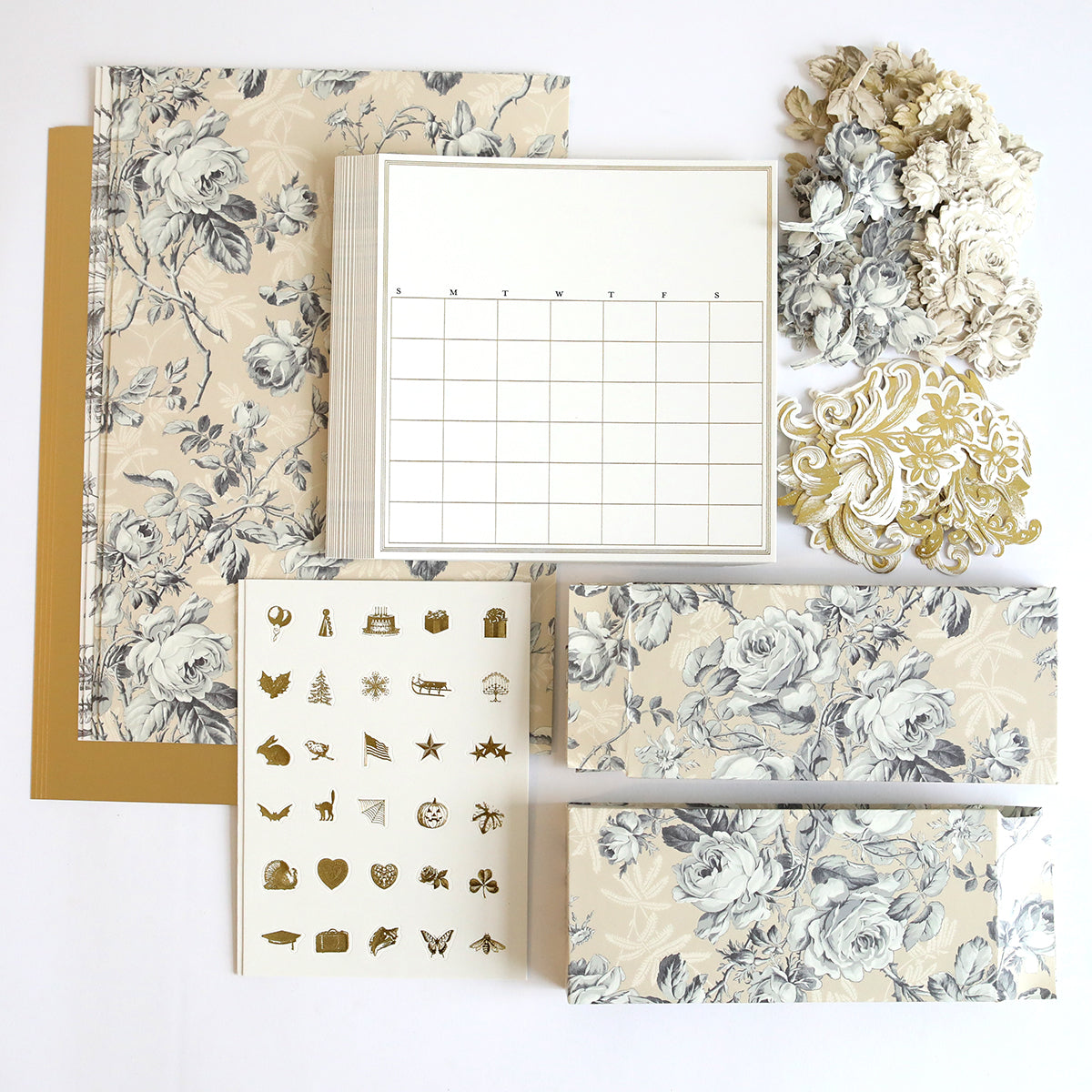 The Creative Calendars Refill Kit, showcasing a variety of stationery items with floral and decorative patterns such as calendars, notebooks, stickers, and ornate cutouts, is elegantly arranged on a flat surface.