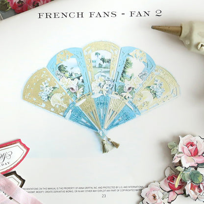 Image of a page featuring "Create 10 Printed Instructions," highlighting an Anna Griffin decorative fan adorned with floral and scenic designs. Surrounded by floral embellishments and a quill pen on the side, this composition encapsulates the elegance achievable in just 10 steps.
