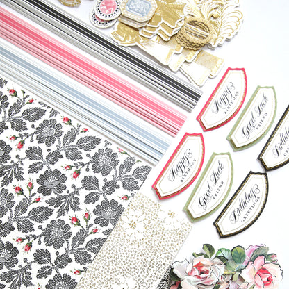 The Stylish Hats Refill Kit, featuring patterned paper, decorative cutouts, and labels with various designs, is spread out on a white surface.