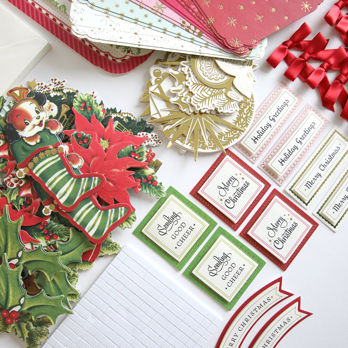 The Simply Retro Christmas Card Making Kit is beautifully arranged on a surface, showcasing Christmas-themed gift tags, cards, and ribbons with a vintage-style Santa card featuring festive decorations and 3D embellishments.