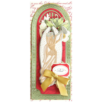 A decorated Christmas card with an angel blowing a trumpet, red background, green border, and a gold bow. Crafted using the Angelic 3D Slimline Dies, the card displays the word "Noel" written in cursive on a small tag. Perfect for spiritual holiday projects.