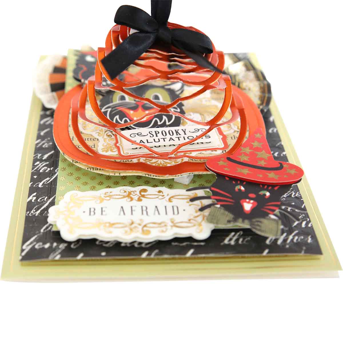 A Pumpkin Kirigami Dies Halloween-themed pop-up card featuring a black bow, the phrase "Spooky Salutations," a witch hat, and the words "Be Afraid," crafted with diecut layers and assorted decorations.