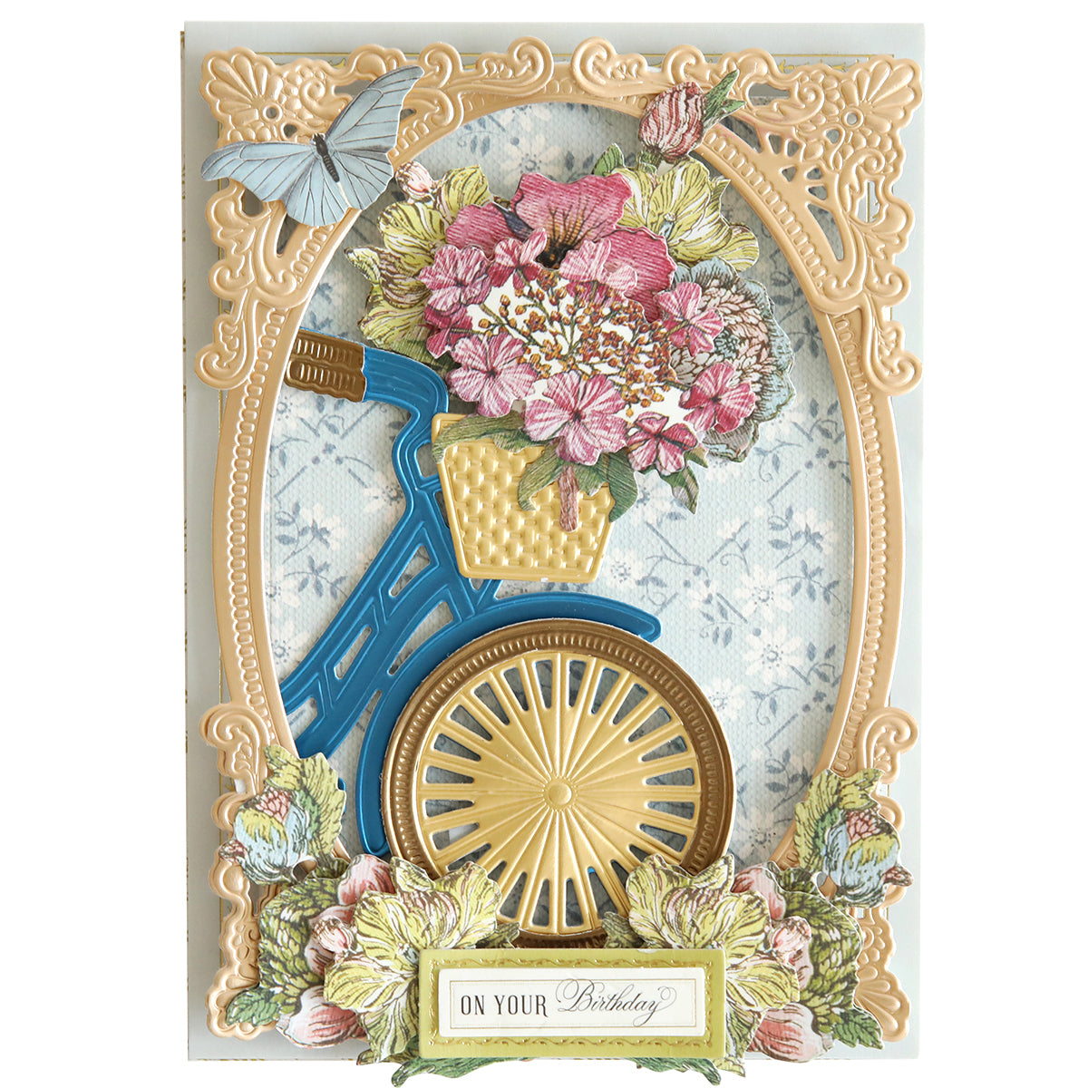 Elaborate birthday card featuring a decorative bicycle frame, a basket of pink flowers, and a blue butterfly at the top left. The bottom shows a label reading "On Your Birthday" adorned with Wildflower Meadow Stickers, which bring the design to life with their 3D effect.