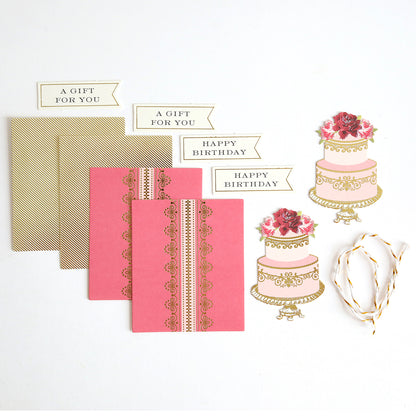 Creative Birthday Tags and Dies crafting set including two pink patterned cards, two gold-striped envelopes, four gift tags, two die-cut tiered cake toppers, and a length of twine.