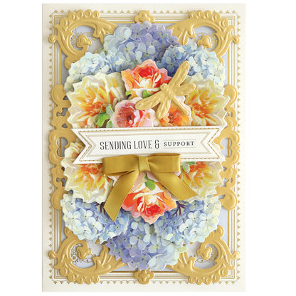 A handmade card showcases a sophisticated floral design, beautifully enhanced by the Album Frame Dies, featuring a golden frame and decorative gold bow. A charming dragonfly accent and the heartfelt message "Sending Love & Support" complete the exquisite piece.