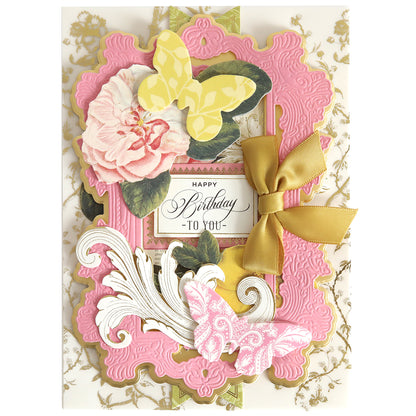 A decorative birthday card featuring Paper Butterfly Embellishments with pink and gold embossed patterns, adorned with a flower and a gold bow. The message reads: "Happy Birthday to You.