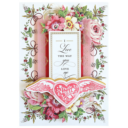 Greeting card with a floral theme showcasing pink and white flowers with decorative gold accents, complete with a heartfelt message, "I love the way you love me," adorned with a winged heart design. Ideal for crafting projects using Smitten Stamps and Dies.