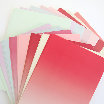 A fan-shaped stack of pastel and gradient paper sheets, ideal for creating flowers with the Posies Flower Mold, Stamps and Dies, displayed on a white surface.