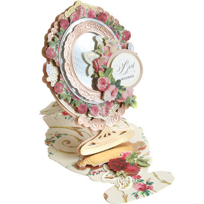 An ornate floral pop-up card called "Mirror Easel Dies" features pink and gold decorations and the text "Best Wishes" for a special occasion.