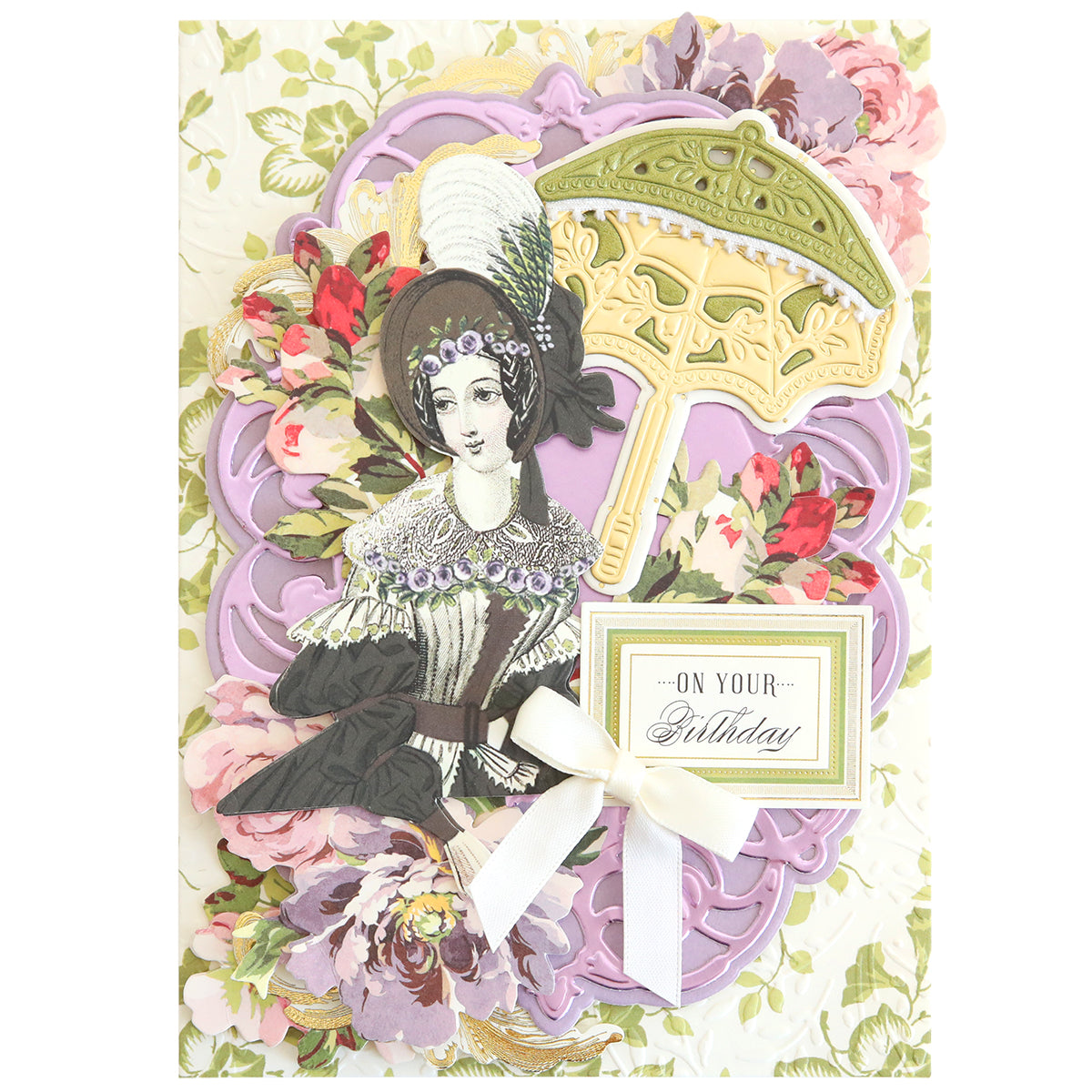 The Victorian Umbrella Dies create a vintage-style birthday card with an elegantly dressed woman holding an umbrella, surrounded by pink flowers and a "On Your Birthday" message. Ideal for card makers looking to add timeless elegance to their crafts.