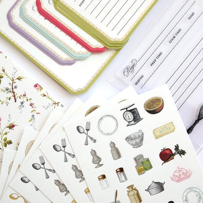 An assortment of stationery with recipe cards, a floral notebook, clear stamps, and kitchen-themed stickers featuring utensils, scales, and food items is available under the "Recipe Card Stamps, Dies and Embellishments" collection.