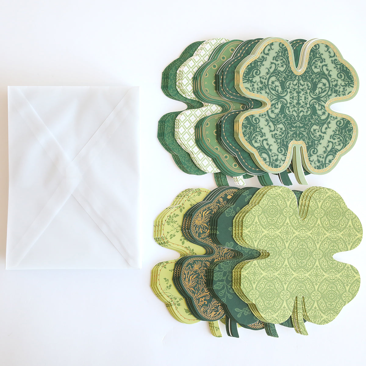 The Shamrock Shaped Cards and Envelopes feature assorted green-patterned shamrock cards conveying good luck, neatly paired with a white envelope on a white background, perfect for St. Patrick's Day celebrations.