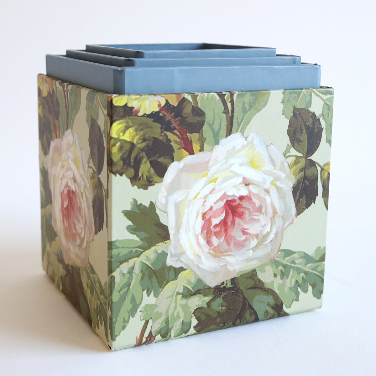 The Francesca Craft Storage box features a floral-patterned design with layers of blue cardstock inside and a large white and pink rose illustration on its side.