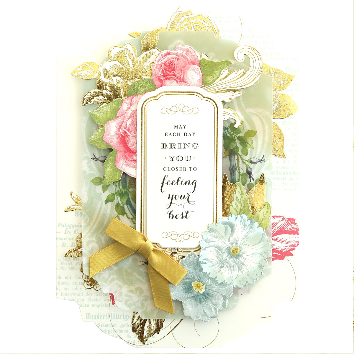 The Simply Get Well Card Making Kit includes a heartfelt card with floral designs, featuring pink roses, a blue flower, and gold accents with a gold ribbon. The text reads: "May each day bring you closer to feeling your best." Includes delicate 3D embellishments for extra charm.