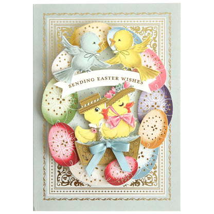 A vintage Easter card with two bluebirds, two yellow chicks in hats and bows, and decorated eggs. Enhanced with "Bunnies and Chicks" embellishment stickers for added charm. Text: "Sending Easter Wishes.