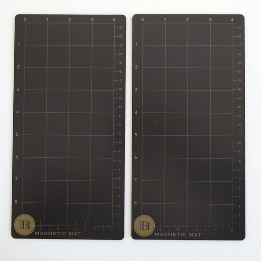 The Empress Elite Mini 5" x 10" Set of 2 Magnet Mats features rectangular black mats with gold grid lines and scales, each labeled "MAGNETIC MAT" with a circular "B" logo—ideal magnetic surfaces for precise die cutting.