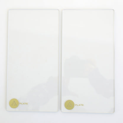 Two rectangular transparent die cutting plates, each with a gold label reading "PLATE" and a stylized "A," are side by side on a white surface—ideal for your Empress Elite Mini 5" x 10" Full Plate Set.