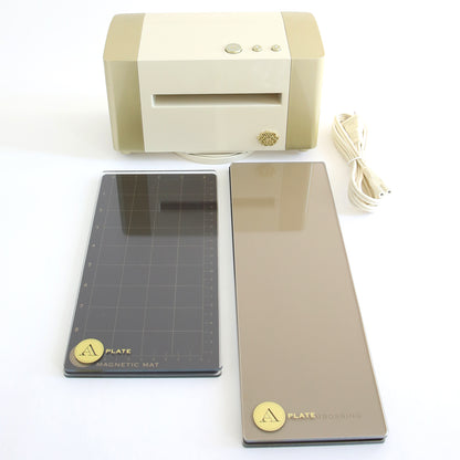 A beige and white Empress Elite Mini Machine with 5" x 10" and 13" plates, labeled "Magnetic Mat" and "Embossing," plus a coiled power cord, is displayed on a white surface.