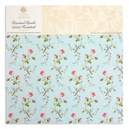 A light blue cardstock cover showcases a pattern of pink roses and green stems, with "Anna Griffin, Windmill 12x12 Cardstock" on top. Ideal for elegant designs using the Windmill Easel Dies.