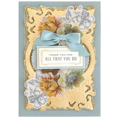 Decorative card featuring gold accents, floral designs made with rub on transfers, a blue ribbon, and a central plaque that reads “Thank you for all that you do”—an ideal addition to your scrapbook supplies or the Ultimate Francesca Papercrafting Collection with Rub Ons.