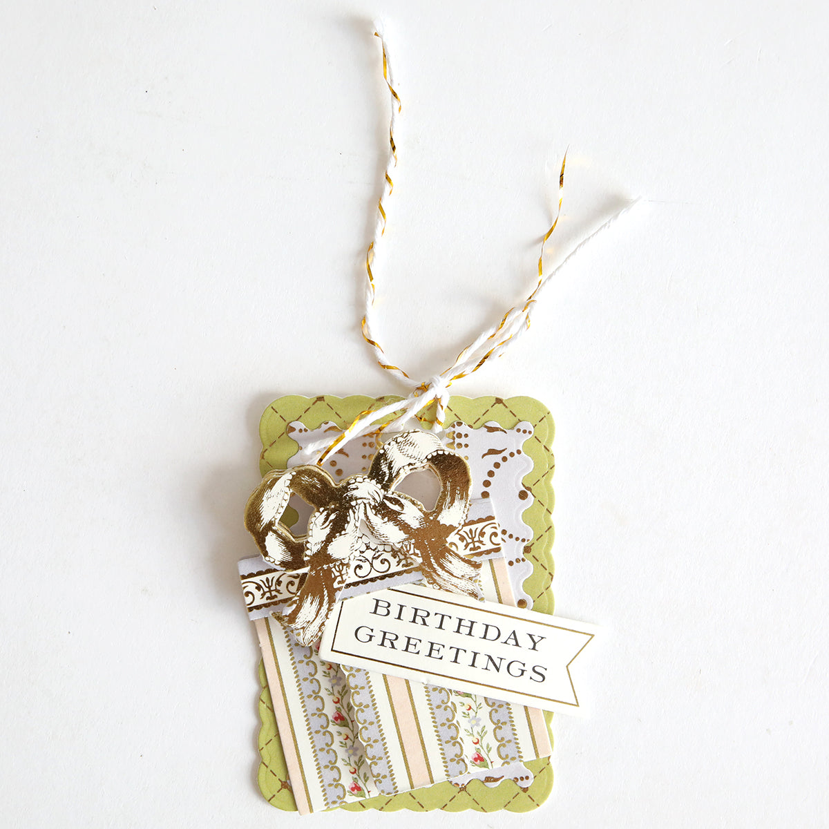 Creative Birthday Tags and Dies featuring a gold foil bow and a banner that reads “BIRTHDAY GREETINGS,” tied with white and gold twine.