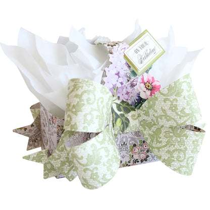 Create unique gifts with Bow Box Dies—use a floral-patterned treat box, large green bow, white tissue paper, and a flower-adorned "Happy Birthday" tag for a charming presentation.